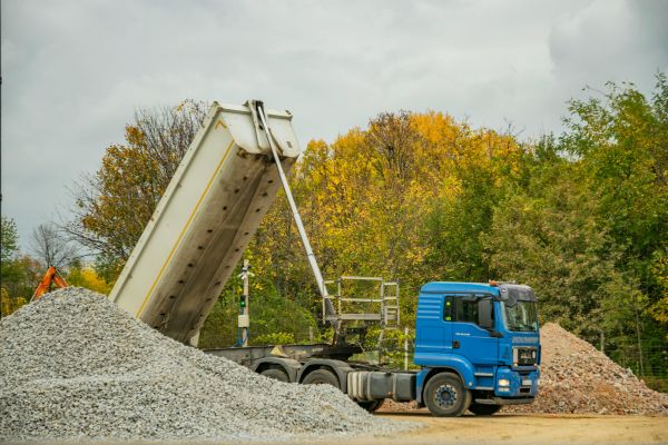 This image is about a dump trailer buying guide. In this image a dump trailer is dumping in a yard